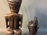 two wooden sculptures of a man and a woman sitting on a table