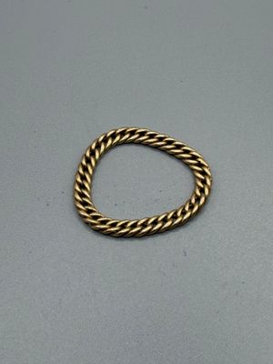 gros plan d'une bague en or sur une surface grise