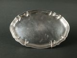 une assiette en argent posée sur une table noire, avec un fond noir