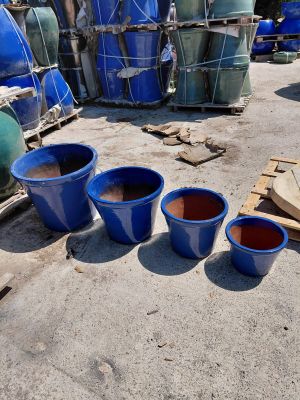 three blue buckets sitting on the ground next to a pile of barrels