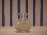 a glass vase sitting on a table in front of a striped wall