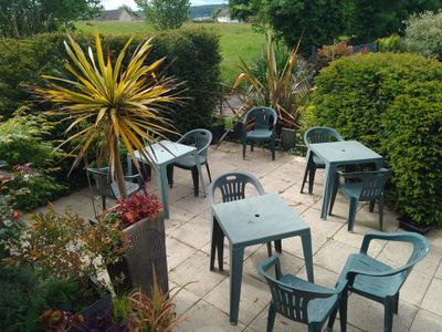 des tables et des chaises sur une terrasse donnant sur un champ verdoyant