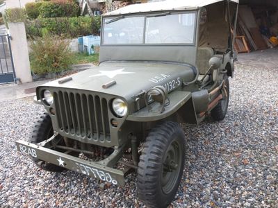 une jeep verte garée sur un parking en gravier