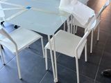 une table en verre avec des chaises blanches et une chaise blanche