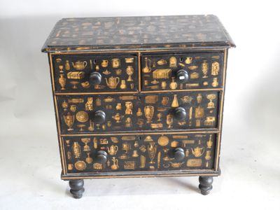 une commode noire et dorée sur laquelle sont posés de nombreux objets