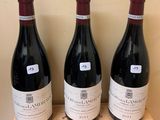 three bottles of wine sit on top of a wooden box