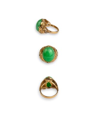 three gold rings with green stones on them on a white surface
