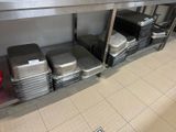 many trays of food sitting on a shelf in the kitchen