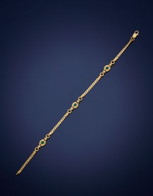 a gold bracelet with a green stone on a blue background