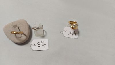 deux paires de bagues en or et en argent et une pierre accompagnée d'une étiquette indiquant son prix