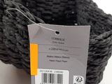 a black basket with a tag on it on a white surface