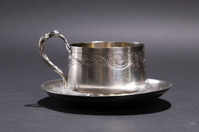 une tasse et une soucoupe en argent posées sur une assiette