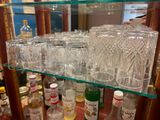 many glasses and bottles of alcohol on a shelf