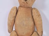 un ours en peluche marron assis sur une surface blanche