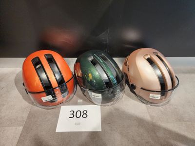 Trois casques sont alignés sur une table, accompagnés d'une étiquette de prix