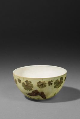 a green and white bowl with leaves on it