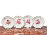 quatre assiettes ornées de motifs floraux sont alignées sur une table