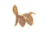 a close up of a gold brooch with leaves on it