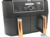 une friteuse à air chaud noire et dorée posée sur un plan de travail blanc
