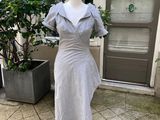 une robe grise posée sur un mannequin devant une porte