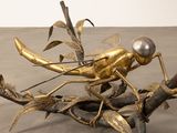 a statue of a bug on a branch with a pearl