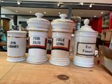 several white and gold canisters on a wooden table in a store