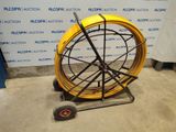 a close up of a yellow hose on a cart in front of a wall