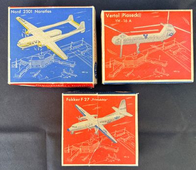 trois boîtes contenant des maquettes d'avions, posées sur une surface noire