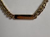 a close up of a gold chain with a bar on it
