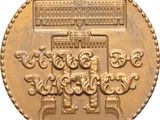 a close up of a gold coin with a building in the background