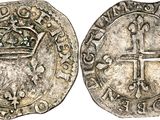 a silver coin with a crown and cross on it