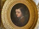 painting of a young man in a gold frame on a table