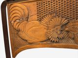 a wooden carving of a rooster and flowers on the back of a chair