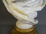 a white marble bust with a gold base and a white cloth draped over it