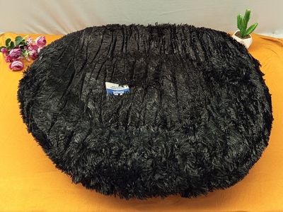 a black round pillow on a yellow table