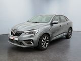 Une voiture grise est garée dans une pièce aux murs blancs.