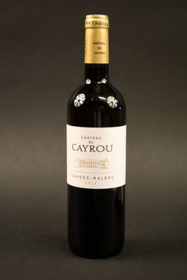 the bottle of red wine is sitting on a black surface
