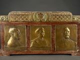 an image of a gold - plated chest with three portraits of men
