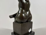 bronze sculpture of a woman sitting on a black marble base