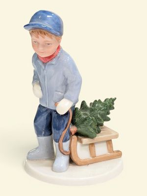 une figurine représentant un garçon portant un traîneau sur lequel est posé un arbre