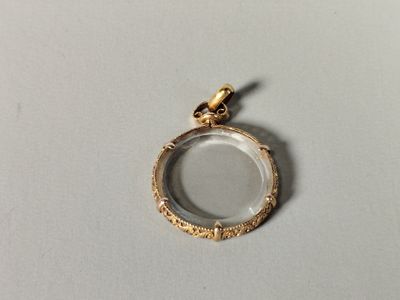 gros plan d'un pendentif plaqué or sur une surface blanche