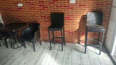 tables and chairs in a room with a brick wall in the background