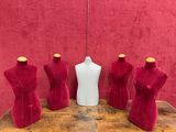 three mannequins and a bottle on a table in front of a red wall