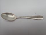 silver plated spoon with a long handle on a white surface
