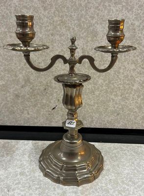 un candélabre ancien en métal argenté, sur lequel sont disposées trois bougies