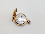 une image d'une montre de poche en or sur une surface blanche