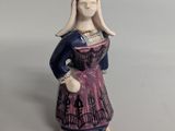 une figurine représentant une femme en robe violette