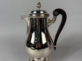 a silver coffee pot with a wooden handle on a white surface
