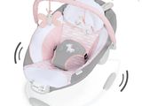 Le berceau du bébé est rose et blanc, orné de notes de musique tout autour.