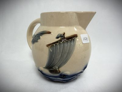 a small pitcher with a boat on it on a table